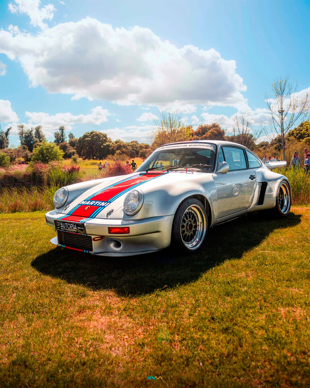 Autopía 2 Madrid. Porsche 911 RSR gris metalizado con vinilos. Un coche clásico alemán en una pradera cerca de un pequeño lago