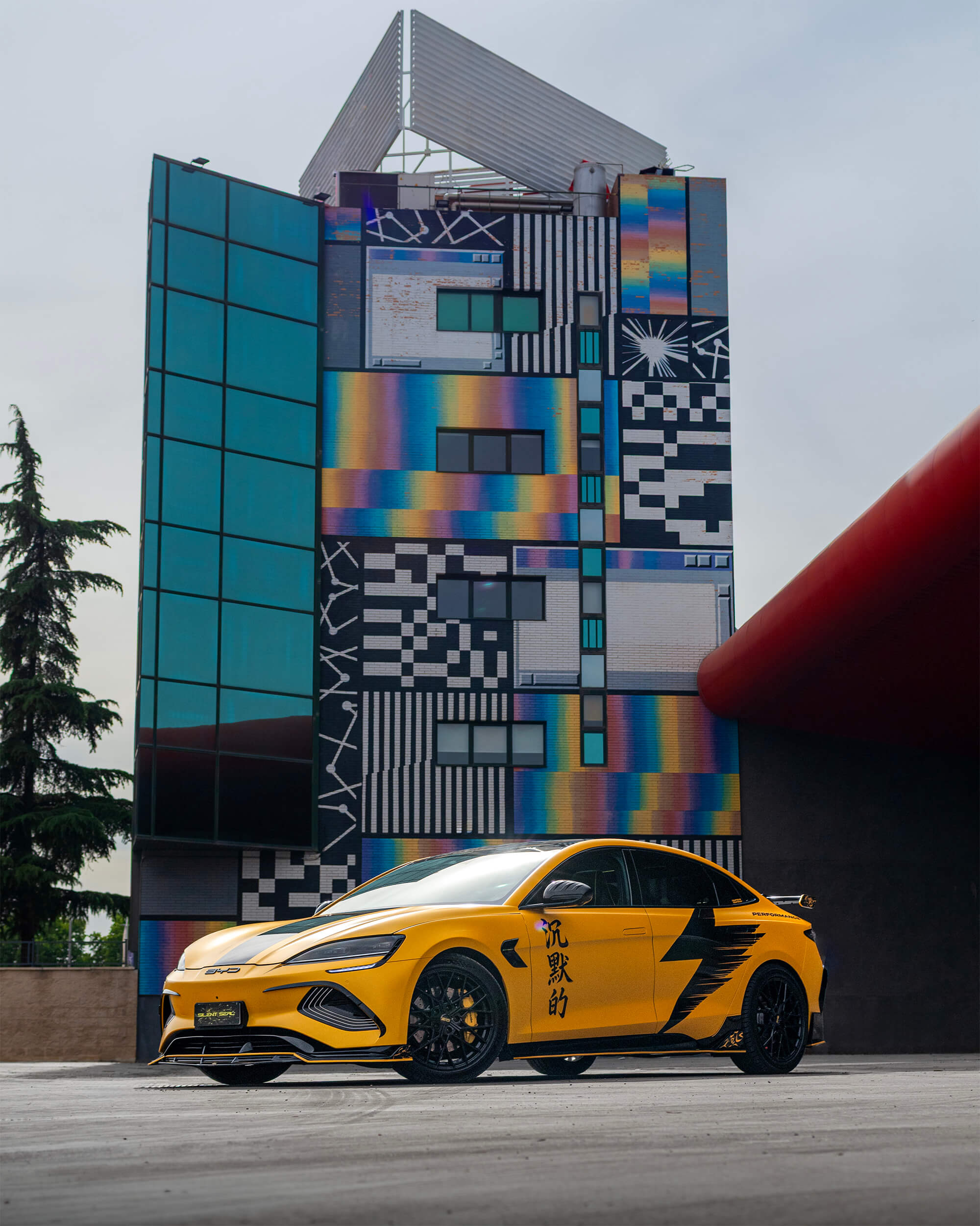 BYD Seal Performance amarillo frente a un edificio industrial de arquitectura colorida