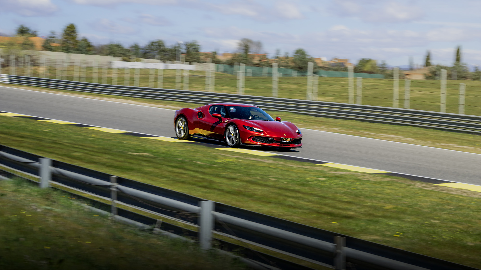 Ferrari 296 gtb rojo rodando por una curva del Circuito del Jarama