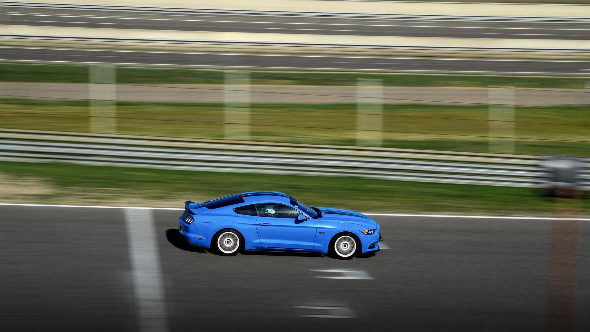 Ford Mustang azul rodando por la pista del Circuito del Jarama